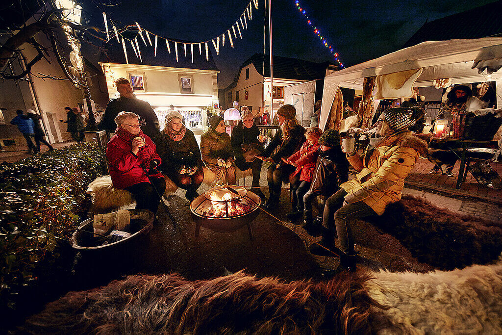 Eine Gruppe Menschen sitzt um ein Lagerfeuer herum
